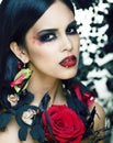 Pretty brunette woman with rose jewelry, black and red, bright make up kike a vampire closeup red lips Royalty Free Stock Photo