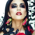 Pretty brunette woman with rose jewelry, black and red, bright make up kike a vampire closeup red lips Royalty Free Stock Photo