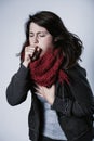 Pretty brunette woman wearing jacket and scarf and coughing