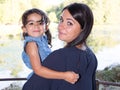 brunette woman in lakeside with cute daughter girl in arms