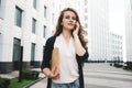 Pretty business woman hold paper documents and discuss financial news on smartphone stand among urban space Royalty Free Stock Photo