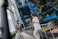 Pretty business woman in white suit and sunglasses using phone during break standing near modern office building with electric Royalty Free Stock Photo