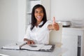 Pretty businesswoman showing thumb up to camera at her desk Royalty Free Stock Photo