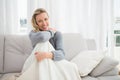 Pretty casual woman sitting on couch under a blanket