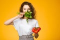 Pretty caucasian girl with curly hair holding vegetables