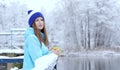 Pretty Caucasian girl dreaming looking into the distance standing outdoor with cup of tea near waterside. Royalty Free Stock Photo