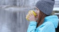 Pretty Caucasian girl dreaming looking into the distance standing outdoor with cup of tea near waterside. Royalty Free Stock Photo