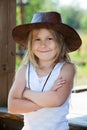 Pretty Caucasian girl standing with crossing hands with leather cowboy hat on head