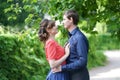 Pretty caucasian love couple walking in the green summer park, having smiles, kisses and hugs Royalty Free Stock Photo