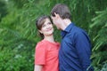 Pretty caucasian love couple walking in the green summer park, having smiles, kisses and hugs Royalty Free Stock Photo