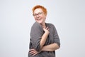 Pretty caucasian mature woman with short red hairstyle in simple pulover is shy to hear a compliment.