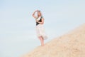 Young beautiful Caucasian woman in white dress and brown leather waistcoat posing in desert landscape with sand. Royalty Free Stock Photo