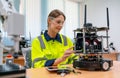 Pretty Caucasian professional engineer or technician worker woman check and maintenance small robotic machine that put on table in Royalty Free Stock Photo
