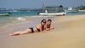 Pretty Caucasian Scandinavian women with teenage son sunbathing at the wet sand close to sea waves, tropical beach, blurry