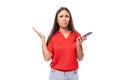 Pretty caucasian woman with black hair is wearing a red blouse with a halter neckline and is holding a phone Royalty Free Stock Photo