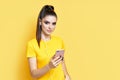 Pretty caucasian woman listening to music from her phone and headphones over yellow background Royalty Free Stock Photo