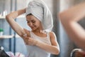 Pretty Caucasian woman shaving her underarm with razor near looking glass at home