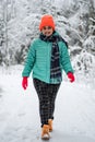 A pretty caucasian young woman in a winter wonderland enjoying the snow fashion walk wearing colourful jacket and red cap Royalty Free Stock Photo