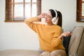 Pretty Asian woman relaxing in her living room, listening her favorite song through her headphones Royalty Free Stock Photo