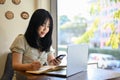 Pretty Asian female college student doing her homework at the coffee shop Royalty Free Stock Photo