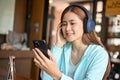 Young Asian female college student using smartphone and listening to music on headphones Royalty Free Stock Photo