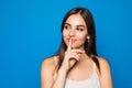 Pretty charming young woman having secret while holding finger on lips and showing silence sign while standing on blue background Royalty Free Stock Photo