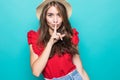 Pretty charming young woman having secret while holding finger on lips and showing silence sign while standing on blue background Royalty Free Stock Photo