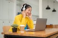 A pretty Asian female student enjoys listening to music on her headphones while doing her homework Royalty Free Stock Photo
