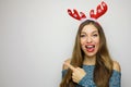 Pretty cheerful christmas woman gesturing with finger and showing away on gray background. Copy space. Royalty Free Stock Photo