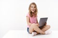Pretty cheerful little kid girl sit crossed legs, hold laptop, studying at home, excited learn new information, studying