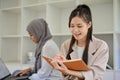 Asian female college student is reading a book in the campus library co-working space Royalty Free Stock Photo