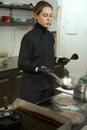 Pretty chef frying meat in frying pan, woman in overalls Royalty Free Stock Photo