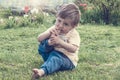 A pretty child bites his toenails. A two year old kid will put his dirty foot in his mouth. A boy sits on the grass on a summer da Royalty Free Stock Photo