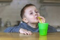 Pretty child drinks a cold drink through a plastic straw in the kitchen Royalty Free Stock Photo