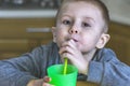 Pretty child drinks iced tea through a plastic straw in the kitchen Royalty Free Stock Photo