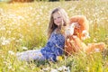 Pretty child girl in camomile field with toy bear Royalty Free Stock Photo
