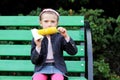 Pretty child girl eats a boiled corn outdoors