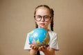 Cute little girl with globe. Child girl with glasses in white t-shirt. School Education Concept. Royalty Free Stock Photo