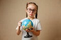 Pretty child girl with glasses at home dreaming of travel and tourism, exploring the world map and globe Royalty Free Stock Photo