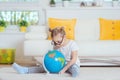 Pretty child girl at home dreaming of travel and tourism, exploring the world and globe Royalty Free Stock Photo