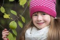 Pretty child girl wearing warm winter clothes holding tree branch with green leaves in cold weather outdoors Royalty Free Stock Photo