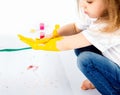 Pretty child girl smears yellow paint on hands Royalty Free Stock Photo