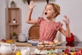 Little girl is making a homemade cake with an easy recipe at kitchen against a white wall with shelves on it. Royalty Free Stock Photo