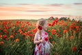 Pretty child young cute girl red dress stood in big poppy flower field countryside landscape view poppies dusk sunset golden hour