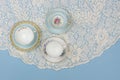 Pretty china teacups on pale blue background with white lace Royalty Free Stock Photo