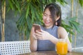 Pretty Chinese Asian woman using internet on mobile phone enjoying relaxed sending text social media chat at coffee shop outdoors Royalty Free Stock Photo