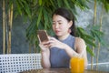 Pretty Chinese Asian woman using internet on mobile phone enjoying relaxed sending text social media chat at coffee shop outdoors Royalty Free Stock Photo