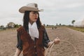 Pretty Chinese cowgirl throwing the lasso in a horse paddock