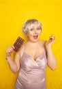 Pretty chubby girl with chocolate bar on yellow studio solid background