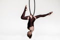 Pretty circus aerialist in brown leotard is spinning upside down on an aerial ring. A young woman performs acrobatic Royalty Free Stock Photo